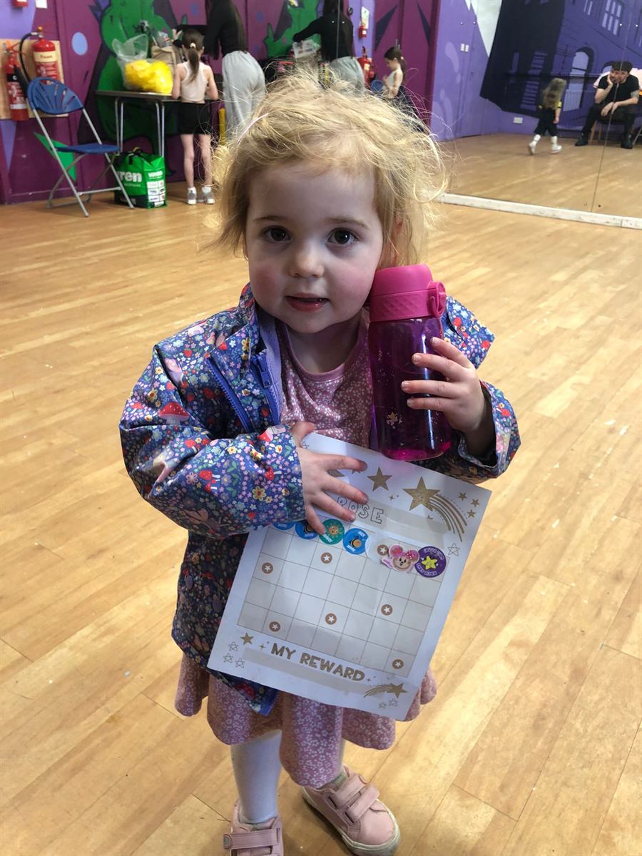 A Mini Geeks child proudly showing her reward chart after class